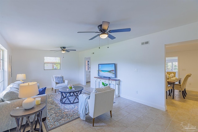 living area featuring visible vents, a healthy amount of sunlight, a ceiling fan, and baseboards