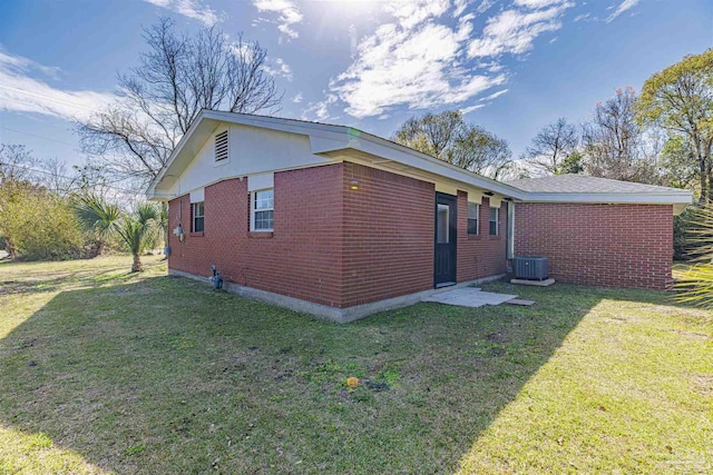 view of side of property with brick siding, a lawn, and cooling unit