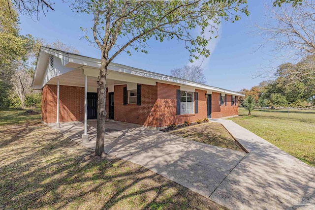 single story home with brick siding, an attached carport, driveway, and a front yard