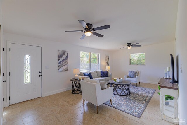 living area with baseboards, light tile patterned flooring, and a ceiling fan