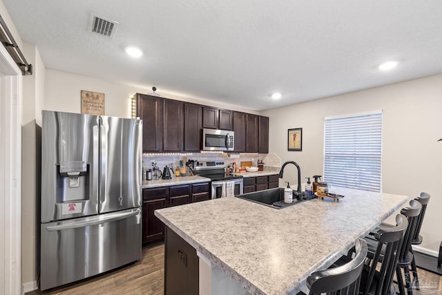 4678 Perception Cir, Milton, FL 32570 - kitchen featuring stainless steel appliances, dark brown cabinets, a sink, dark wood finished floors, and a breakfast bar