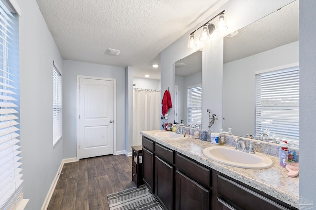 4678 Perception Cir, Milton, FL 32570 - bathroom featuring wood finished floors, baseboards, double vanity, a textured ceiling, and a shower with curtain