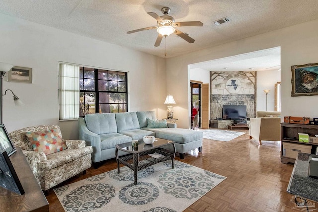 living area with a textured ceiling, visible vents, and a ceiling fan