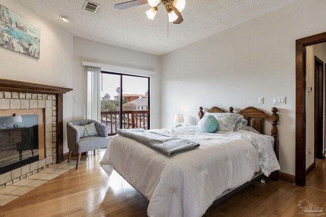 bedroom featuring access to outside, a fireplace, visible vents, and wood finished floors