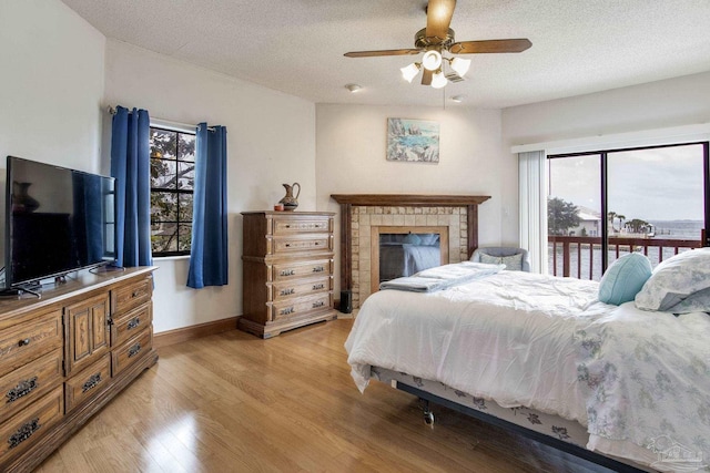 bedroom featuring light wood-style floors, access to outside, multiple windows, and a textured ceiling