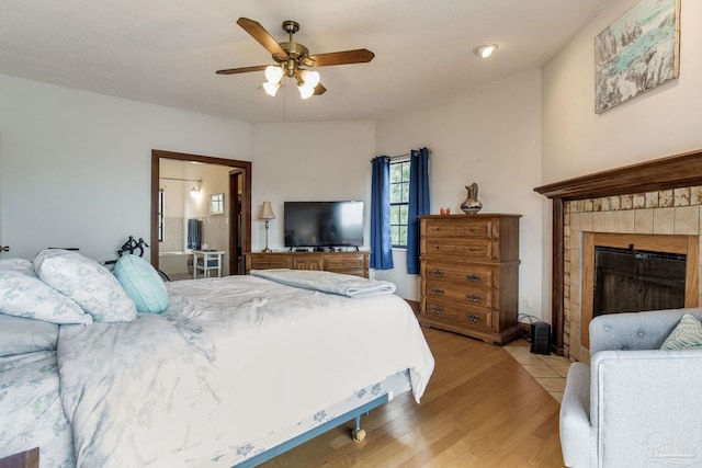 bedroom with ceiling fan, light wood-type flooring, and a fireplace with flush hearth