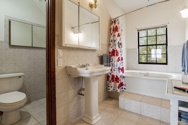 bathroom with tile walls, tiled tub, toilet, and tile patterned floors