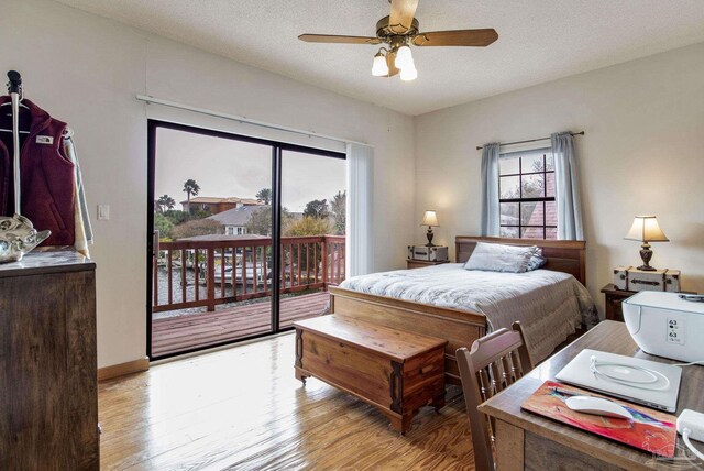 bedroom with access to exterior, a textured ceiling, and wood finished floors