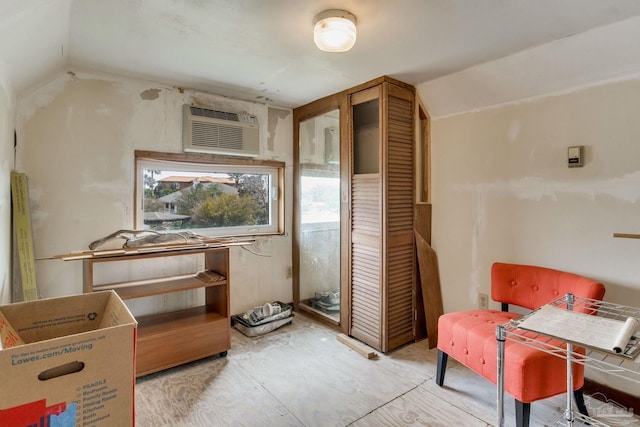 living area featuring vaulted ceiling and an AC wall unit