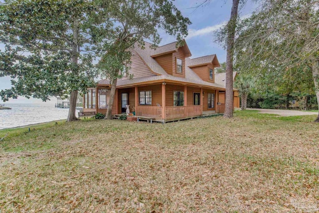 view of front of house featuring a water view, a front lawn, and roof with shingles