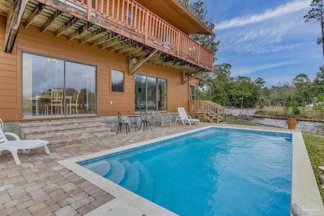 rear view of house with a patio and an outdoor pool