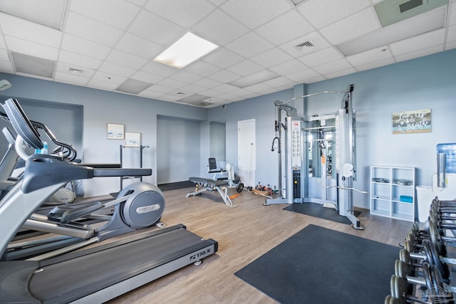 exercise room with hardwood / wood-style floors and a drop ceiling