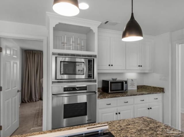 kitchen featuring pendant lighting, stainless steel appliances, dark stone countertops, and white cabinets