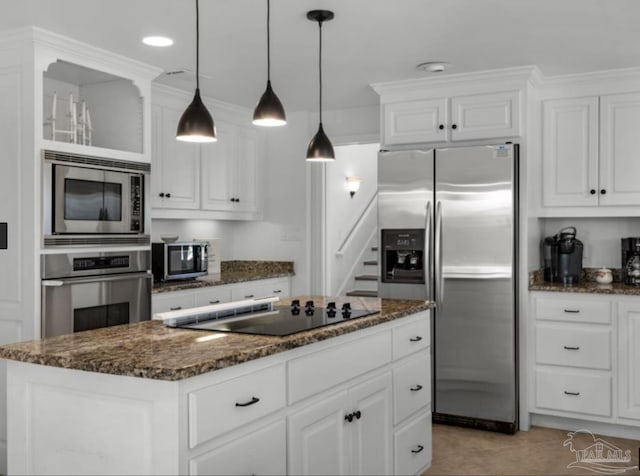 kitchen with white cabinetry, hanging light fixtures, dark stone countertops, stainless steel appliances, and a kitchen island