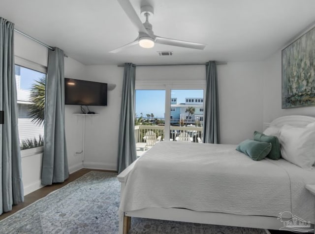 bedroom featuring multiple windows, access to exterior, dark hardwood / wood-style flooring, and ceiling fan