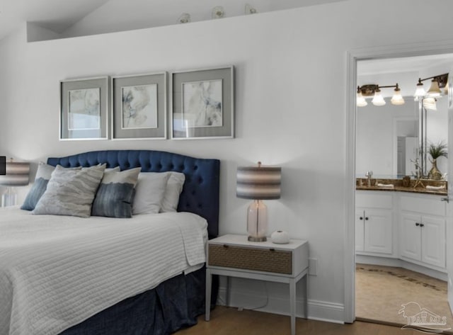 bedroom featuring hardwood / wood-style flooring, connected bathroom, sink, and vaulted ceiling