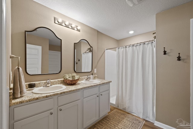 5711 Guinevere Ln, Milton, FL 32583 - full bath featuring a textured ceiling, a sink, a shower with curtain, and wood finished floors