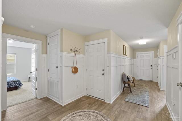 5711 Guinevere Ln, Milton, FL 32583 - entryway featuring a textured ceiling, wood finished floors, wainscoting, and a decorative wall