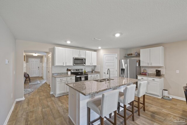 5711 Guinevere Ln, Milton, FL 32583 - kitchen featuring stainless steel appliances, tasteful backsplash, light wood-style flooring, and a sink