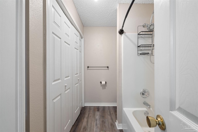 bathroom featuring  shower combination, hardwood / wood-style floors, and a textured ceiling