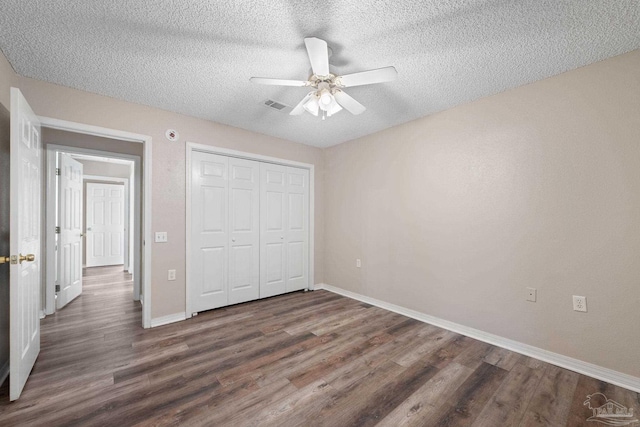 unfurnished bedroom featuring ceiling fan, dark hardwood / wood-style floors, a textured ceiling, and a closet