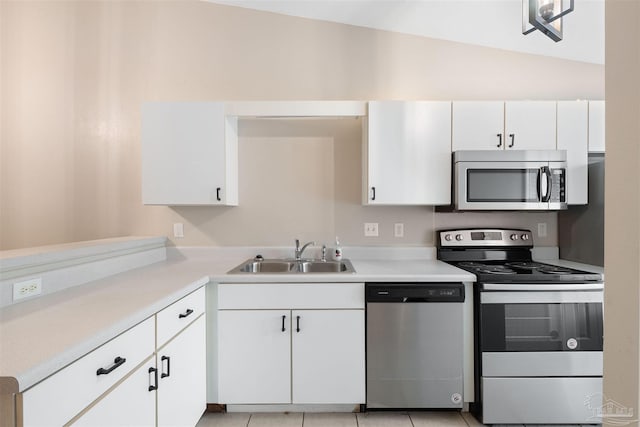 kitchen featuring white cabinetry, sink, light tile patterned floors, and appliances with stainless steel finishes