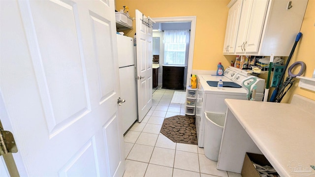 laundry room with washing machine and clothes dryer, cabinets, and light tile patterned floors