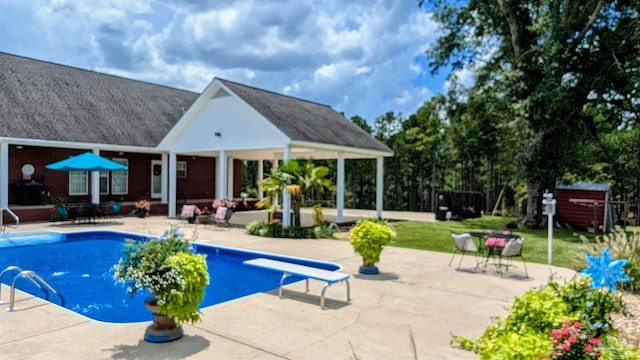 view of swimming pool with a diving board and a patio area