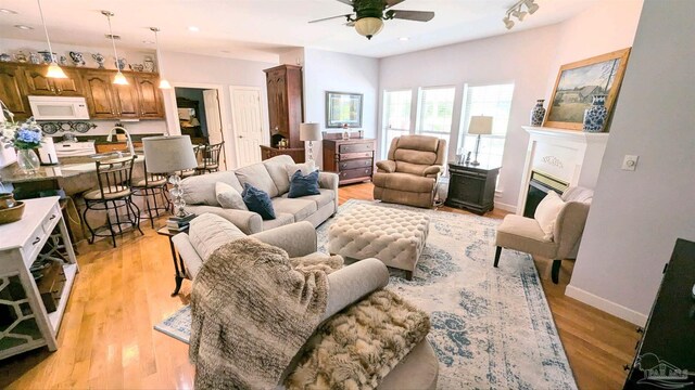 living room with sink, light wood-type flooring, and ceiling fan