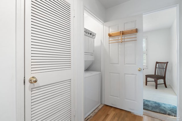 laundry area with light wood-type flooring, stacked washer / drying machine, and laundry area