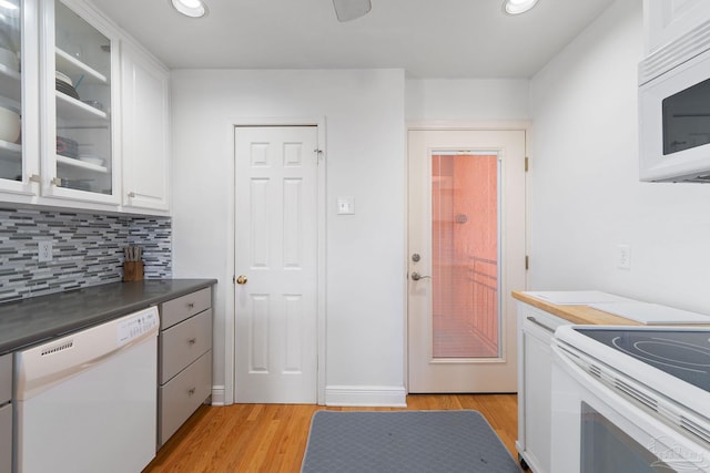 kitchen with white appliances, tasteful backsplash, glass insert cabinets, white cabinetry, and light wood-style floors