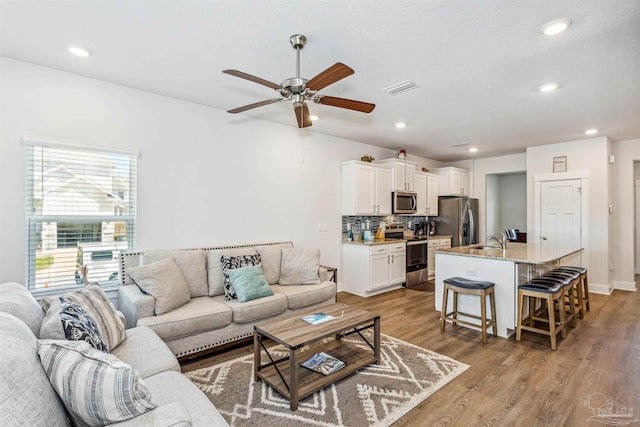 living room with ceiling fan, sink, and light hardwood / wood-style flooring