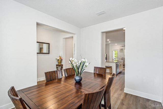 dining space with wood-type flooring and a textured ceiling