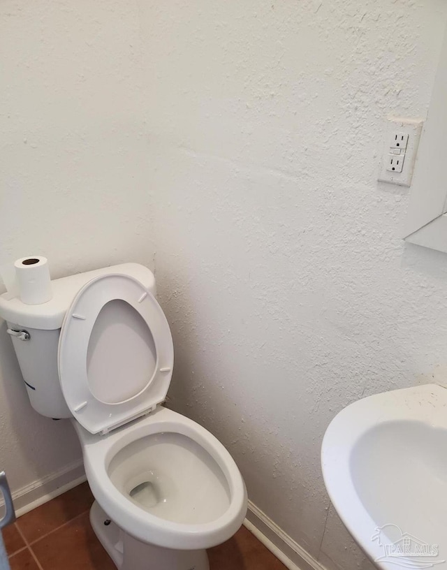 bathroom with toilet, a sink, and baseboards