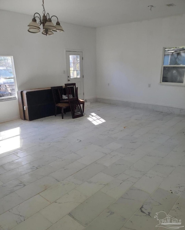 unfurnished living room featuring baseboards, marble finish floor, and an inviting chandelier