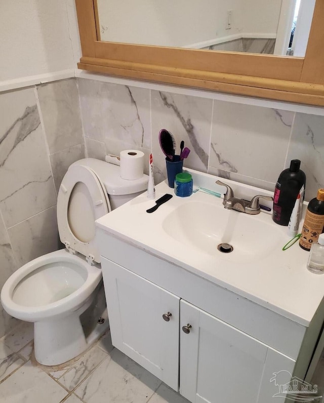 half bathroom with marble finish floor, toilet, and vanity