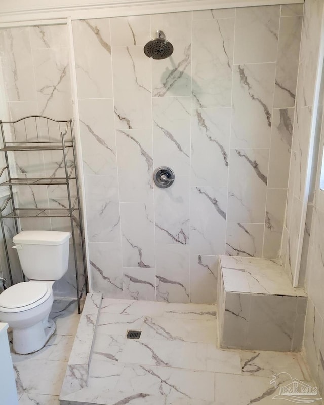 bathroom with marble finish floor, a tile shower, and toilet
