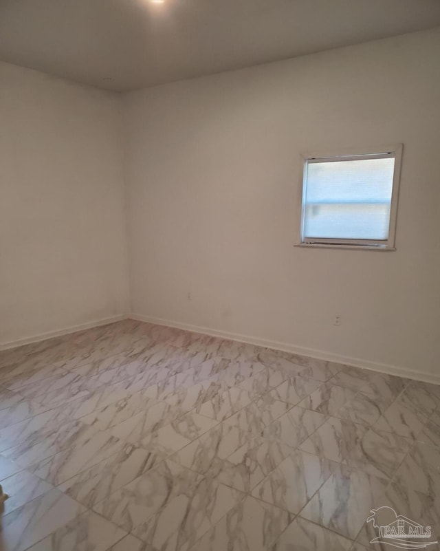 empty room featuring marble finish floor and baseboards