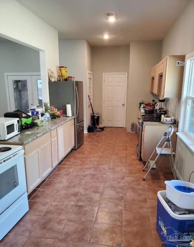 kitchen featuring light stone countertops, visible vents, light tile patterned floors, and appliances with stainless steel finishes