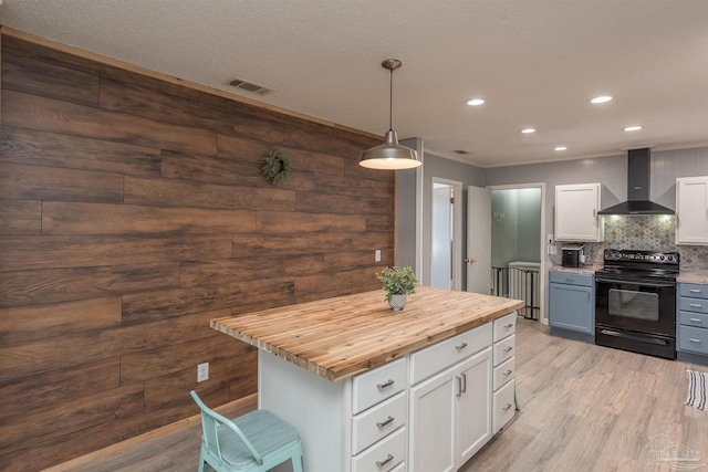 kitchen featuring electric range, visible vents, butcher block counters, wood finished floors, and wall chimney range hood