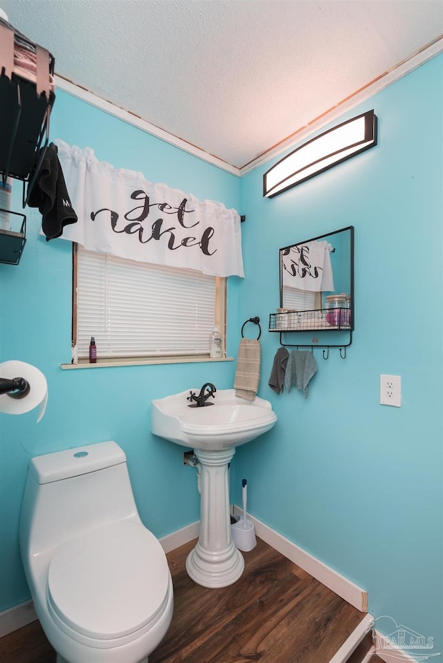 half bathroom featuring baseboards, a textured ceiling, toilet, and wood finished floors