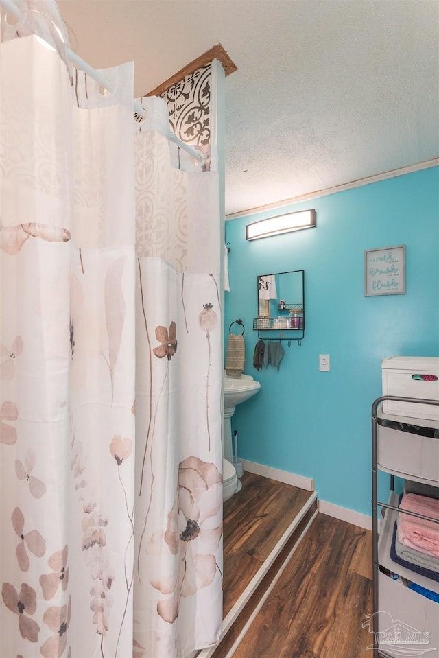 bathroom featuring curtained shower, baseboards, a textured ceiling, and wood finished floors