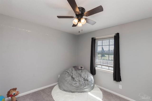 living area featuring ceiling fan, carpet floors, and baseboards