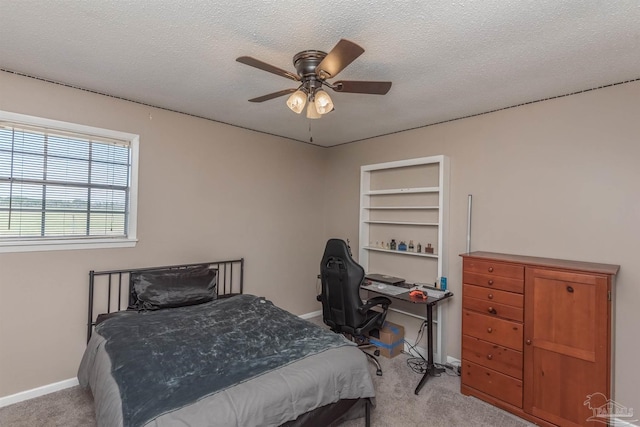 carpeted bedroom with ceiling fan, baseboards, and a textured ceiling