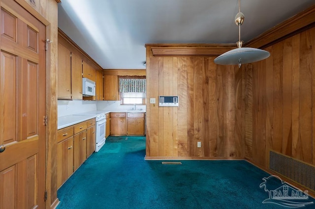 kitchen featuring pendant lighting, wooden walls, white appliances, sink, and carpet flooring