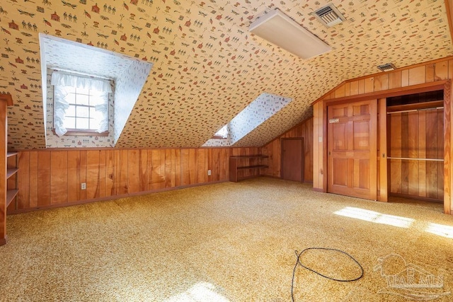 additional living space featuring wooden walls, carpet flooring, and vaulted ceiling with skylight