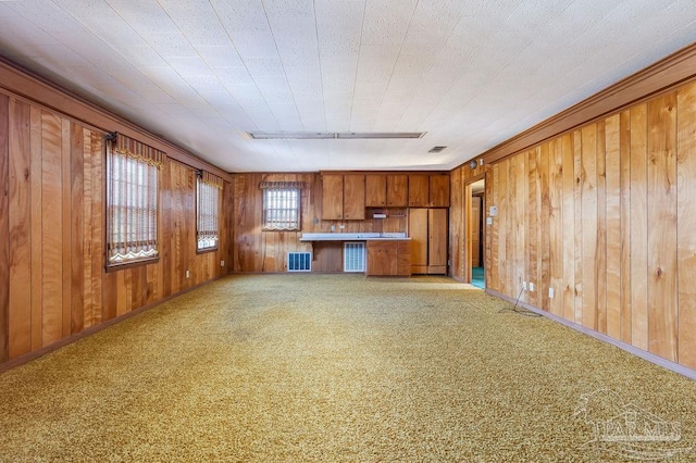 unfurnished living room featuring wood walls and light colored carpet