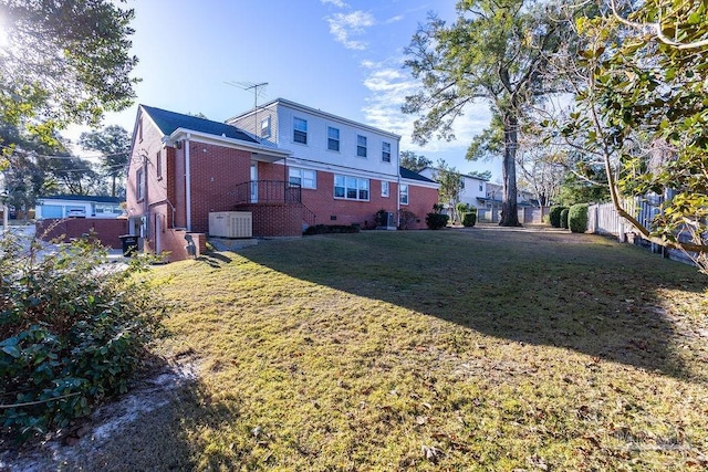 back of property featuring central AC unit and a yard