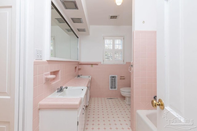 full bathroom with tile walls, tile patterned floors, toilet, and vanity