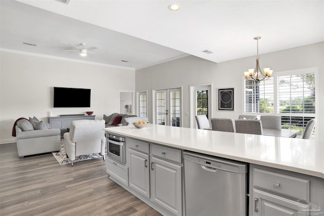 kitchen featuring pendant lighting, gray cabinetry, hardwood / wood-style floors, stainless steel appliances, and ornamental molding